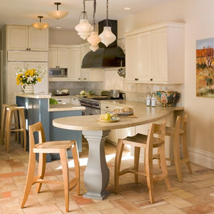 This is an example of a mid-sized contemporary l-shaped open plan kitchen in San Francisco with a farmhouse sink, recessed-panel cabinets, white cabinets, limestone benchtops, beige splashback, stone tile splashback, panelled appliances, terra-cotta floors and with island.