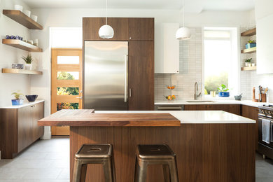 This is an example of a contemporary l-shaped kitchen in Denver with a submerged sink, flat-panel cabinets, medium wood cabinets, grey splashback, stainless steel appliances, an island, grey floors and white worktops.