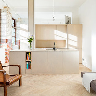 Design ideas for a medium sized contemporary galley open plan kitchen in London with a submerged sink, flat-panel cabinets, light wood cabinets, wood worktops, wood splashback, light hardwood flooring, an island and beige floors.
