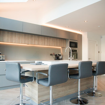 Example of a mid-sized trendy single-wall porcelain tile and beige floor open concept kitchen design in Dublin with quartzite countertops, an island, flat-panel cabinets, beige backsplash, glass sheet backsplash and stainless steel appliances