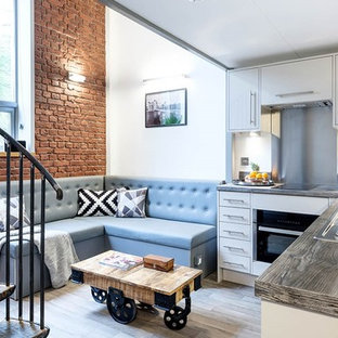 Design ideas for a contemporary l-shaped open plan kitchen in London with a built-in sink, flat-panel cabinets, white cabinets, wood worktops, grey splashback, black appliances, light hardwood flooring, no island and brown worktops.
