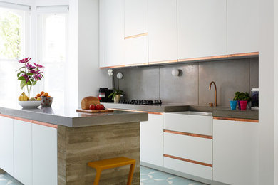 Large contemporary single-wall open plan kitchen in London with concrete worktops, grey splashback, an island, a belfast sink, flat-panel cabinets, white cabinets, cement tile splashback and blue floors.
