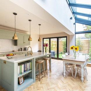 Foto di una cucina tradizionale di medie dimensioni con ante verdi, paraspruzzi bianco, parquet chiaro, isola, pavimento beige, top bianco e ante in stile shaker