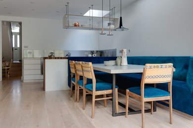 Photo of a medium sized contemporary open plan dining room in London with light hardwood flooring.