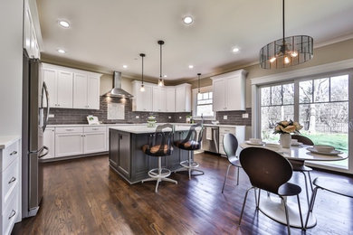 Large trendy u-shaped medium tone wood floor and brown floor eat-in kitchen photo in Chicago with an undermount sink, recessed-panel cabinets, white cabinets, quartzite countertops, gray backsplash, subway tile backsplash, stainless steel appliances and an island