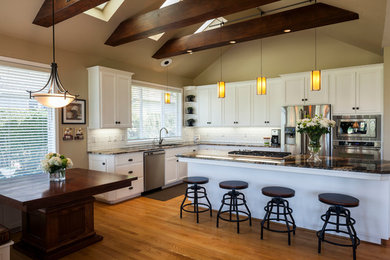 Inspiration for a large timeless l-shaped light wood floor eat-in kitchen remodel in Portland with an undermount sink, recessed-panel cabinets, white cabinets, granite countertops, white backsplash, ceramic backsplash, stainless steel appliances and an island