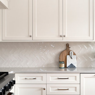 Mid-sized eat-in kitchen designs - Mid-sized l-shaped light wood floor eat-in kitchen photo in Chicago with a farmhouse sink, shaker cabinets, white cabinets, quartz countertops, white backsplash, ceramic backsplash, paneled appliances and an island