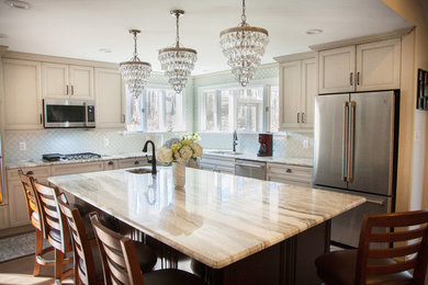 Example of a mid-sized classic u-shaped dark wood floor and brown floor eat-in kitchen design in Other with an undermount sink, recessed-panel cabinets, beige cabinets, limestone countertops, white backsplash, ceramic backsplash, stainless steel appliances, an island and beige countertops