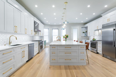 Example of a huge trendy galley light wood floor and brown floor enclosed kitchen design in New York with an undermount sink, stainless steel appliances, shaker cabinets, white cabinets, an island, quartzite countertops, white backsplash, cement tile backsplash and white countertops