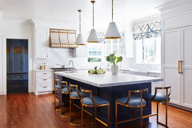 Inspiration for a large transitional l-shaped medium tone wood floor eat-in kitchen remodel in New York with a farmhouse sink, shaker cabinets, white cabinets, marble countertops, white backsplash, marble backsplash, paneled appliances, an island and white countertops