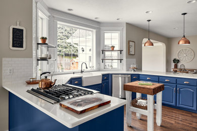 Eat-in kitchen - mid-sized transitional u-shaped dark wood floor eat-in kitchen idea in Portland with a farmhouse sink, raised-panel cabinets, blue cabinets, quartzite countertops, white backsplash, subway tile backsplash, stainless steel appliances, an island and white countertops