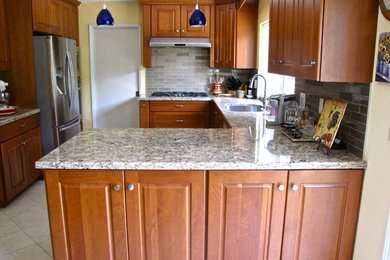 Example of a transitional l-shaped ceramic tile open concept kitchen design in San Francisco with an undermount sink, recessed-panel cabinets, medium tone wood cabinets, granite countertops, metallic backsplash, cement tile backsplash, stainless steel appliances and a peninsula