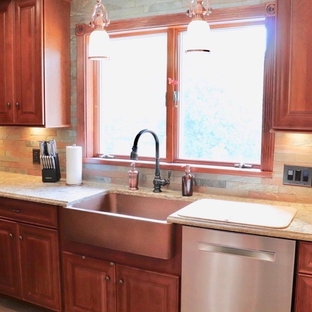 This is an example of a mid-sized traditional u-shaped separate kitchen in New York with a farmhouse sink, raised-panel cabinets, medium wood cabinets, quartz benchtops, brown splashback, slate splashback, stainless steel appliances, vinyl floors, with island, multi-coloured floor and beige benchtop.