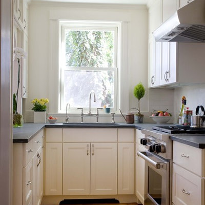 Example of a small classic enclosed kitchen design in Boston with stainless steel appliances, recessed-panel cabinets, white cabinets and white backsplash