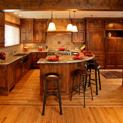 Example of a mountain style kitchen design in Denver with a farmhouse sink, raised-panel cabinets, medium tone wood cabinets, beige backsplash and paneled appliances