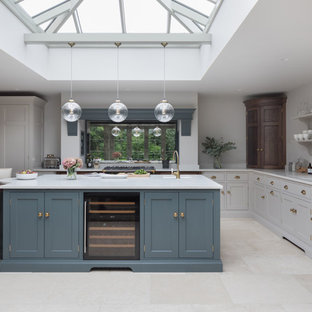 This is an example of a medium sized classic l-shaped kitchen in Essex with a submerged sink, shaker cabinets, grey cabinets, mirror splashback, stainless steel appliances, an island, beige floors and white worktops.