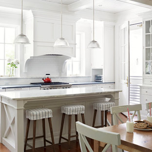 Farmhouse kitchen/diner in Richmond with a belfast sink, white cabinets, granite worktops, white splashback, metro tiled splashback, stainless steel appliances, medium hardwood flooring, an island, shaker cabinets and orange floors.