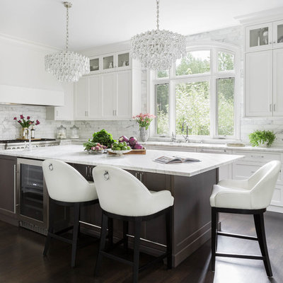 Example of a large transitional u-shaped dark wood floor and brown floor kitchen design in Seattle with an undermount sink, shaker cabinets, white cabinets, marble countertops, white backsplash, marble backsplash, stainless steel appliances and an island