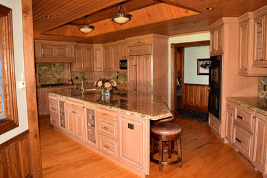 Kitchen - large traditional u-shaped medium tone wood floor and brown floor kitchen idea in Denver with an undermount sink, distressed cabinets, granite countertops, multicolored backsplash, stone slab backsplash, an island, raised-panel cabinets and black appliances