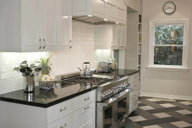ロサンゼルスにある中くらいなトラディショナルスタイルのおしゃれなII型キッチン (サブウェイタイルのキッチンパネル、シルバーの調理設備、白いキッチンパネル、リノリウムの床) の写真