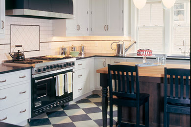 Inspiration for a mid-sized timeless l-shaped linoleum floor enclosed kitchen remodel in Denver with an undermount sink, shaker cabinets, white cabinets, granite countertops, white backsplash, subway tile backsplash, black appliances, an island and black countertops