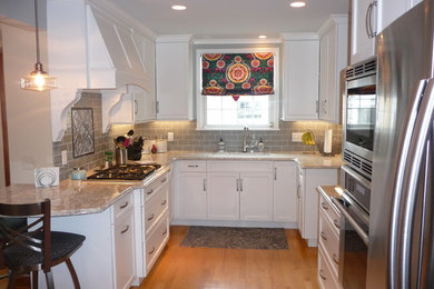 ミルウォーキーにあるおしゃれなキッチン (アンダーカウンターシンク、ガラスタイルのキッチンパネル、シルバーの調理設備、淡色無垢フローリング) の写真