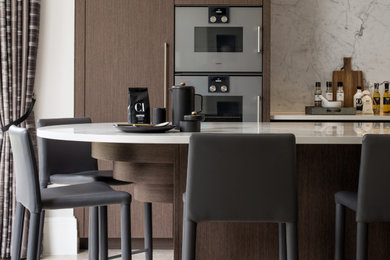 Große Moderne Küche mit flächenbündigen Schrankfronten, dunklen Holzschränken, Kücheninsel und weißer Arbeitsplatte in Surrey