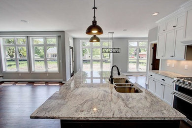 Inspiration for a large transitional l-shaped dark wood floor and brown floor enclosed kitchen remodel in Milwaukee with a triple-bowl sink, shaker cabinets, white cabinets, marble countertops, stainless steel appliances and an island