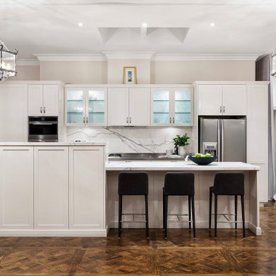 Inspiration for a large transitional galley brown floor and dark wood floor open concept kitchen remodel in Melbourne with shaker cabinets, white cabinets, marble countertops, white backsplash, marble backsplash, stainless steel appliances, an island and white countertops