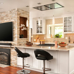Idée de décoration pour une cuisine ouverte tradition avec un placard à porte vitrée, des portes de placard blanches, une crédence beige, une crédence en carrelage métro, un sol en bois brun, une péninsule, un sol orange et un plan de travail beige.