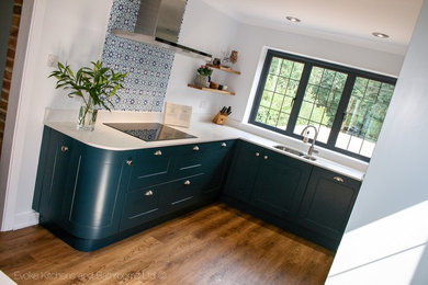 Exemple d'une cuisine chic de taille moyenne avec un placard à porte shaker, des portes de placard bleues, un plan de travail en quartz et un plan de travail blanc.