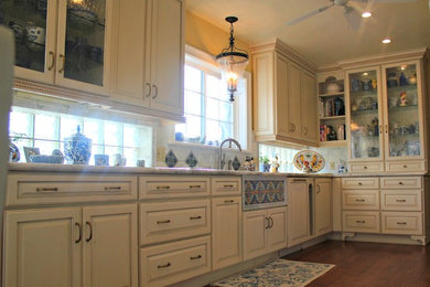 Example of a large classic galley light wood floor enclosed kitchen design in Sacramento with an undermount sink, raised-panel cabinets, beige cabinets, marble countertops and paneled appliances