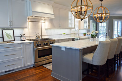 Inspiration for a large transitional single-wall medium tone wood floor eat-in kitchen remodel in Charlotte with a farmhouse sink, shaker cabinets, white cabinets, marble countertops, white backsplash, stone tile backsplash, stainless steel appliances and an island