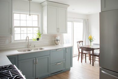 Inspiration for a mid-sized transitional l-shaped light wood floor and beige floor eat-in kitchen remodel in Chicago with an undermount sink, shaker cabinets, quartz countertops, white backsplash, mosaic tile backsplash, stainless steel appliances, no island, white countertops and blue cabinets