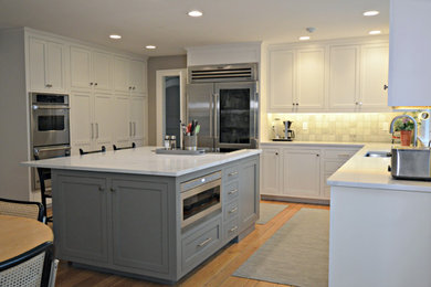Large transitional u-shaped medium tone wood floor and brown floor open concept kitchen photo in New York with an undermount sink, recessed-panel cabinets, white cabinets, quartzite countertops, beige backsplash, stone tile backsplash, stainless steel appliances, an island and white countertops