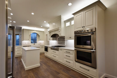Eat-in kitchen - large traditional l-shaped vinyl floor and brown floor eat-in kitchen idea in Other with a farmhouse sink, recessed-panel cabinets, white cabinets, quartz countertops, stainless steel appliances, an island, white backsplash and ceramic backsplash