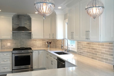 Example of a transitional porcelain tile kitchen design in New York with an undermount sink, shaker cabinets, white cabinets, quartz countertops, gray backsplash, subway tile backsplash, stainless steel appliances and a peninsula