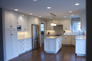 Example of a large transitional u-shaped dark wood floor enclosed kitchen design in Cincinnati with an undermount sink, shaker cabinets, white cabinets, marble countertops, gray backsplash, subway tile backsplash, stainless steel appliances and an island