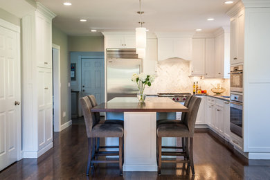 Example of a mid-sized transitional l-shaped dark wood floor and brown floor kitchen pantry design in Boston with an island, an undermount sink, shaker cabinets, white cabinets, wood countertops, beige backsplash, marble backsplash and stainless steel appliances