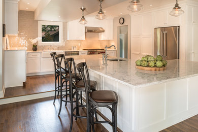 Eat-in kitchen - cottage l-shaped dark wood floor and brown floor eat-in kitchen idea in Indianapolis with a farmhouse sink, shaker cabinets, yellow cabinets, quartz countertops, gray backsplash, stone tile backsplash, stainless steel appliances and an island