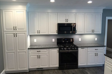 Kitchen - traditional kitchen idea in Boston with raised-panel cabinets, white cabinets and granite countertops