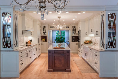 Example of a mid-sized classic galley light wood floor eat-in kitchen design in Chicago with a farmhouse sink, raised-panel cabinets, white cabinets, granite countertops, multicolored backsplash, mosaic tile backsplash, white appliances and an island
