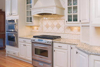 Exempel på ett mellanstort modernt kök, med en undermonterad diskho, luckor med upphöjd panel, vita skåp, granitbänkskiva, beige stänkskydd, stänkskydd i porslinskakel, rostfria vitvaror, ljust trägolv och en köksö