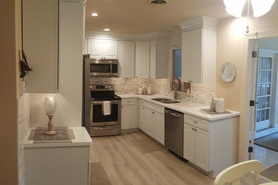 This is an example of a small l-shaped kitchen/diner in Other with a submerged sink, raised-panel cabinets, white cabinets, engineered stone countertops, white splashback, porcelain splashback, stainless steel appliances and no island.
