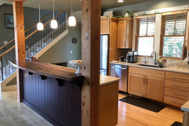 Example of a mid-sized transitional l-shaped medium tone wood floor open concept kitchen design in Portland with an undermount sink, flat-panel cabinets, light wood cabinets, quartz countertops, multicolored backsplash, ceramic backsplash, stainless steel appliances, an island and white countertops