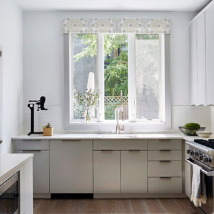 Small transitional enclosed kitchen ideas - Inspiration for a small transitional u-shaped light wood floor enclosed kitchen remodel in New York with an undermount sink, flat-panel cabinets, gray cabinets, quartz countertops, white backsplash, ceramic backsplash, paneled appliances and no island