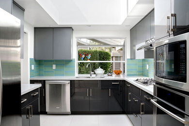 Mid-sized trendy l-shaped ceramic tile enclosed kitchen photo in Orange County with a double-bowl sink, flat-panel cabinets, gray cabinets, quartz countertops, green backsplash, glass tile backsplash, stainless steel appliances and no island