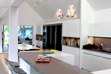 Источник вдохновения для домашнего уюта: большая угловая кухня в современном стиле с обеденным столом, плоскими фасадами, белыми фасадами, серым фартуком и техникой из нержавеющей стали