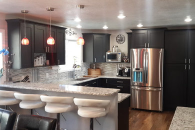Eat-in kitchen - mid-sized contemporary u-shaped medium tone wood floor eat-in kitchen idea in Denver with an undermount sink, shaker cabinets, black cabinets, multicolored backsplash, glass tile backsplash, stainless steel appliances, no island and granite countertops