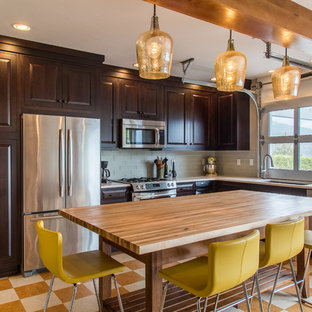 Mid-sized transitional l-shaped open plan kitchen in Portland with dark wood cabinets, glass tile splashback, stainless steel appliances, with island, an undermount sink, raised-panel cabinets, quartz benchtops, green splashback, linoleum floors and multi-coloured floor.